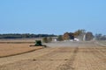 Combine harvesting soybeans with farm scene in background