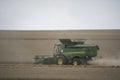 The combine harvests the ripe golden wheat in the grain field. Agricultural work in summer.