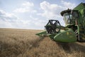 The combine harvests ripe wheat in the grain field. Agricultural work in summer. Detail of the combine close-up.