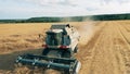 Combine is reaping ripe wheat while riding along the field