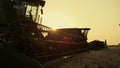 Combine silhouette at golden sunset farmland. Seasonal grain harvesting time. Royalty Free Stock Photo