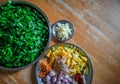 Combined indian spices and ingredients for making spinach curry ( indian cuisine ) with wooden background