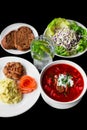 Combo set with borscht, mashed potato, black bread, salad on black background side view