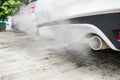 Combustion fumes coming out of white car exhaust pipe, air pollution concept