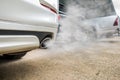 Combustion fumes coming out of white car exhaust pipe, air pollution concept