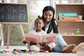 Come join us for story time. a woman reading a book to her daughter while sitting at home.