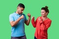 Come on let`s fight! Portrait of lovely couple in casual wear standing together. isolated on green background