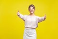 Come into my arms. Portrait of friendly beautiful woman with fair hair in casual beige blouse, isolated on yellow background