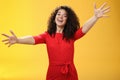 Come into my arms. Portrait of friendly and loving, caring charming woman with curly hair in red casual dress spread Royalty Free Stock Photo