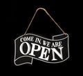 Come in we are open. Black and white sign with a string to hang it, on black background Royalty Free Stock Photo