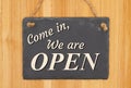 Come in we are open type message on a hanging chalkboard sign