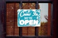 Come in we are open. Worn signpost in vintage style on an old shop door Royalty Free Stock Photo