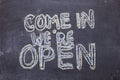 Come in we`re open. Chalk lettering on blackboard. Multi colored inscription Royalty Free Stock Photo