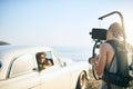 Come take a ride. a focused young man shooting a scene with people in a car with a state of the art video camera outside