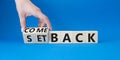 Comeback and setback symbol. Hand turns a cube and changes the word setback to comeback. Beautiful blue background. Businessman