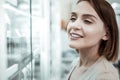 A comely female looking at the drugstore window with pills.