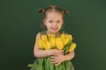 Comely girl in green dress is hugging bouquet of tulips as gift to mother