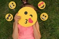 Comely pleasant girl covers her face with a smiley face that sends an air kiss