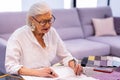 Comely smiling elderly woman in glasses making designer sketch