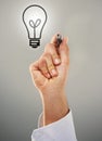 He always comes up with bright ideas. a man holding a marker wit the image of a lightbulb above his hand. Royalty Free Stock Photo