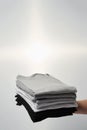 Comfort and easy wear. Male hand holding stack of multi colored t-shirts againtst grey background