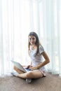 Comfort working at home. Pretty young woman using laptop while sitting on the floor near window Royalty Free Stock Photo