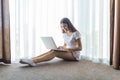Comfort working at home. Pretty young woman using laptop while sitting on the floor near window Royalty Free Stock Photo