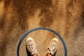 Comfort Zone Concept. Male on Sneaker Shoes Standing inside a Circle Line, Top View, Grunge Dirty Concrete Floor with Sunlight as