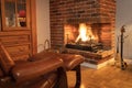 Comfortable armchair and footrest in front of a fireplace in winter. Royalty Free Stock Photo