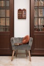 Comfortable armchair with pillow and book between wooden bookcases in library Royalty Free Stock Photo