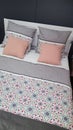 Comfortable bed with design coverlet and pink pillows in grey bedroom interior Royalty Free Stock Photo