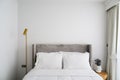 Comfortable bed in modern bedroom, pillows and white soft blanket on bed, lamp and vase decorate in room. Free white wall space Royalty Free Stock Photo