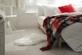 Comfortable bed with warm checkered plaid in stylish room interior Royalty Free Stock Photo