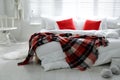 Comfortable bed with warm checkered plaid in stylish room interior Royalty Free Stock Photo