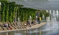 Comfortable benches with climbing Aristolochia plant under pergola. Fountain Three streams turning into complex of fountains