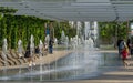 Comfortable benches with climbing Aristolochia plant under pergola. Fountain Three streams turning into complex of fountains