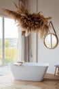 Comfortable bright bathroom with a boho-chic interior design, a free-standing white bath against the background of a panoramic Royalty Free Stock Photo