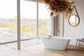 Comfortable bright bathroom with a boho-chic interior design, a free-standing white bath against the background of a panoramic Royalty Free Stock Photo