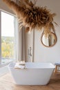 Comfortable bright bathroom with a boho-chic interior design, a free-standing white bath against the background of a panoramic Royalty Free Stock Photo