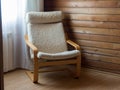 A comfortable chair in the corner near the window. Wooden walls. Cozy interior