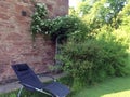 A comfortable lounge chair stands in the garden near a brick wall as a place of rest