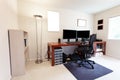 Computer chair at large work table with computer monitors and other technology equipment in bright home office interior