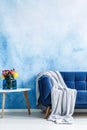 Comfortable dark blue settee with gray blanket and small side ta Royalty Free Stock Photo