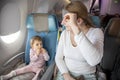 Comfortable flight with a child. little cute toddler girl sitting in an airplane chair at the porthole and looking at Royalty Free Stock Photo