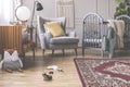 Comfortable grey armchair with yellow pillow between retro cabinet and wooden crib in mid century baby room interior Royalty Free Stock Photo