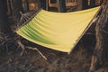 A comfortable hammock hangs between the trunks of pine trees near a country house in the forest