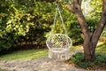 Comfortable hanging wicker white chair in summer garden. Cozy hygge place for weekend relax in garden. Hammock chair in boho style Royalty Free Stock Photo