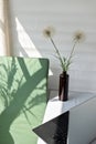 Comfortable home office workspace, laptop computer on table, vase with dandelion flowers, green chair with abstract Royalty Free Stock Photo