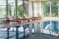 Comfortable indoor swimming pool in country house with chaise lounges, massage bed and rocking chair