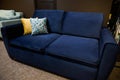 Comfortable minimalist stylish navy blue sofa with yellow and patterned cushion in the furniture store exposition center. Home